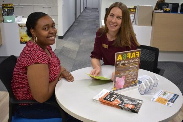 Financial Aid director and student sitting at a table smiling